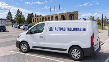 Фургон autoabitallinnas.ee с фирменным маячком перед управой волости Сауэ. Клиенту, ожидающему у дороги, дают светоотражающий жилет.