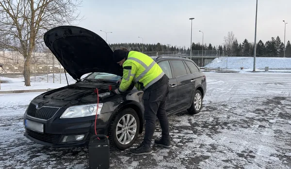 Technician jump-starting a dark estate car in a snowy car park; a diesel gets two glow-plug preheat cycles before cranking.